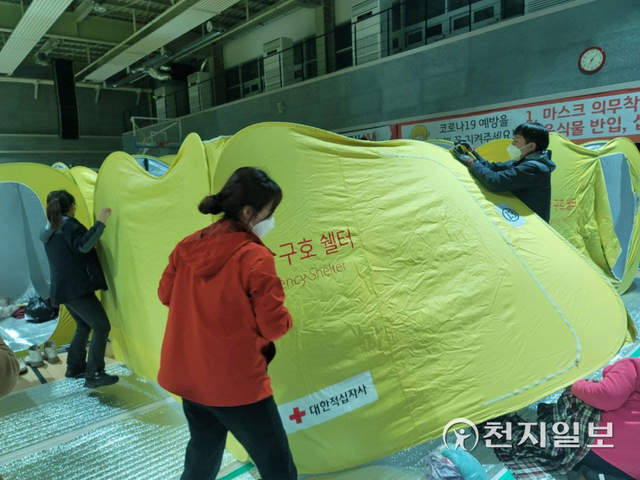 [천지일보 울진=송해인 기자] 경북 울진 산불이 확산 중인 5일 산불로 집을 잃은 이재민들이 울진국민체육센터에 마련된 대피소에 머무는 가운데 울진군청 관계자들이 이재민들을 위해 재난구호쉘터를 설치하고 있다. ⓒ천지일보 2022.3.5