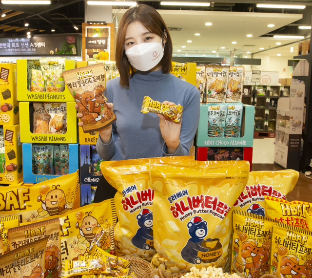 모델이 홈플러스가 창립 25주년을 기념해 길림양행 바프(HBAF)와 공동 기획한 스낵 4종과 OB라거와 협업한 팝콘 등 신제품 5종을 선보이고 있다. (제공: 홈플러스)