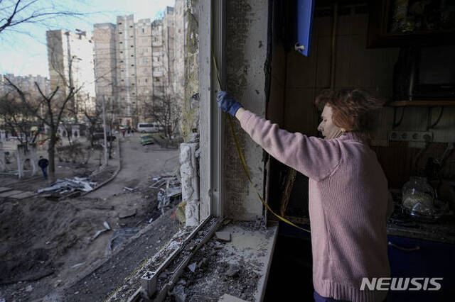 [키이우=AP/뉴시스] 21일(현지시간) 우크라이나 키이우에서 주민이 러시아군의 포격으로 파손된 건물에서 창문 수리를 하고 있다. 2022.03.22.