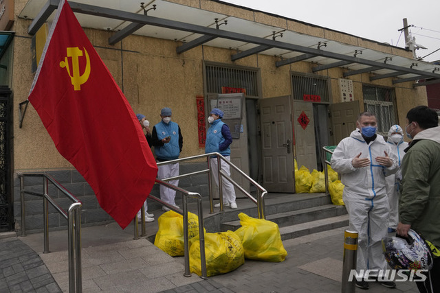 [베이징=AP/뉴시스] 17일 중국 베이징의 봉쇄 구역 밖에서 시 근로자들이 중국 공산당 깃발과 유해 폐기물 쓰레기봉투 근처에 모여 이야기를 나누고 있다. 중국의 코로나19 확진자가 급증하는 가운데 시진핑 국가주석은 