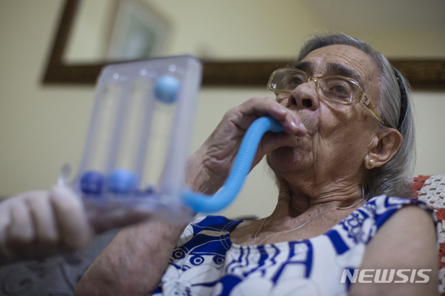 [리우데자네이루=AP/뉴시스]지난해 12월 코로나19로 입원해 삽관했던 리아 타바레스(91) 할머니가 13일(현지시간) 브라질 리우데자네이루 자택에서 폐활량 운동을 하고 있다.