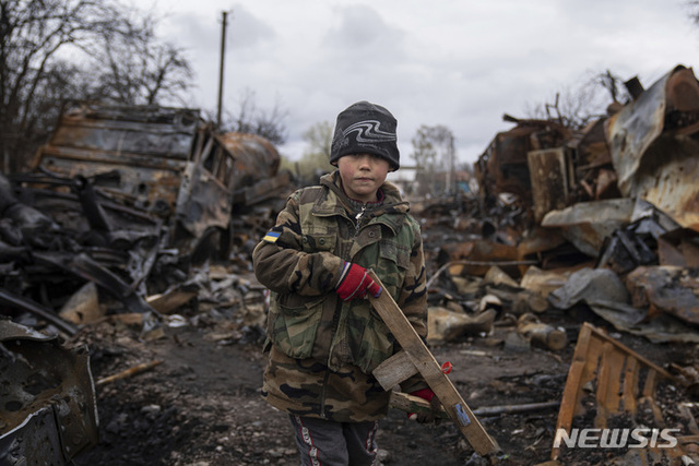 [체르니히우=AP/뉴시스] 지난 17일(현지시간) 우크라이나 체르니히우에서 나무로 만든 장난감 총을 든 한 소년(7)이 파괴된 러시아군 차량 옆에서 총놀이를 하고 있다.