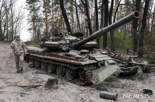 [키이우=AP/뉴시스]19일(현지시간) 한 우크라이나 군인이 키이우 인근 지역에서 전투 후 버려진 러시아군 탱크 옆을 지나고 있다. 2022.04.19