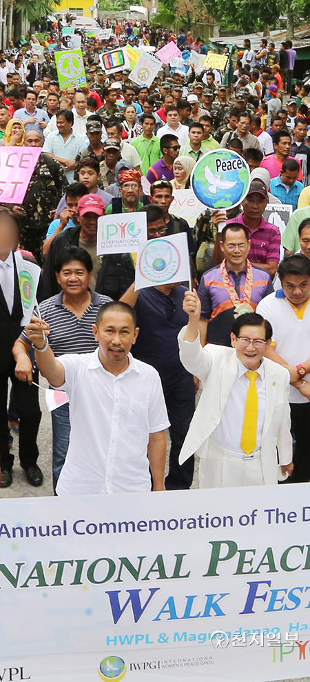 2015년 5월 25일 필리핀 민다나오 마긴다나오주 블루안체육관에서 세계평화선언문 2주년 기념식이 진행됐다. 이 대표(맨 앞 오른쪽)와 마긴다나오 주지사(맨 앞 왼쪽)가 기념식 후 진행된 평화걷기대회에서 주민들과 걸으며 만국기를 흔들고 있다. (제공: HWPL)ⓒ천지일보 2022.5.5