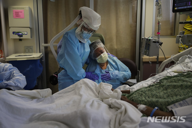 2020년 7월 31일 미국 캘리포니아 풀러턴에 있는 주드 메디컬 센터 코로나19 병동에서 로멜레아 나바로(오른쪽)이 죽어가는 남편 안토니오 머리맡에 앉아 눈물을 흘리며 간호사 미셸 영킨의 위로를 받고 있다. (출처: 뉴시스)