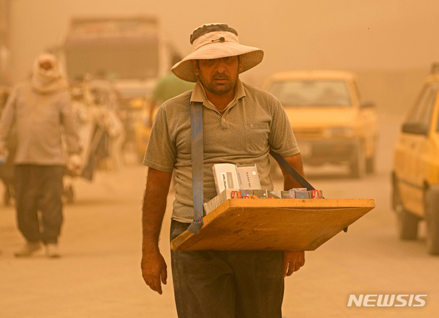 [바그다드=AP/뉴시스] 16일(현지시간) 이라크 바그다드에 모래폭풍이 불어오는 동안 한 거리 상인이 담배를 팔고 있다.