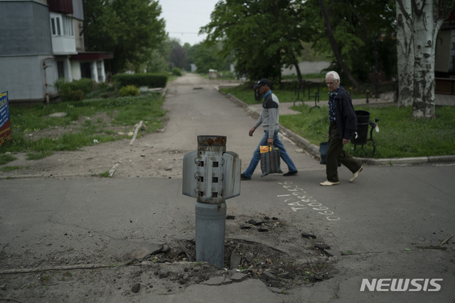 [리시찬스크=AP/뉴시스] 13일(현지시간) 우크라이나 루한스크주 리시찬스크에서 주민들이 도로에 박힌 로켓 주변을 지나고 있다.