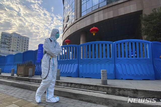 작년 2월 6일 중국 우한중앙병원 밖에서 보호용 작업복과 소독장비를 착용한 근로자가 걷고 있다. (출처: 뉴시스)