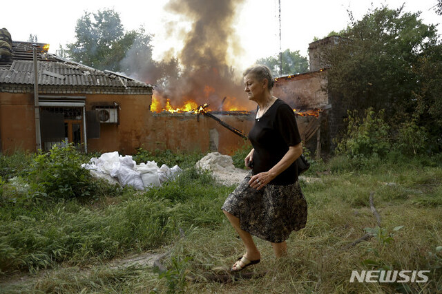 지난 3일(현지시간) 우크라이나 동부 도네츠크 인민공화국 정부 관할 구역에서 한 여성이 포격당해 불타는 집으로부터 도망치고 있다. (출처: 뉴시스)