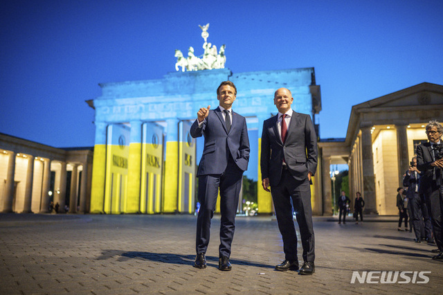[베를린=AP/뉴시스] 독일을 방문한 에마뉘엘 마크롱(왼쪽) 프랑스 대통령이 9일(현지시간) 베를린 브란덴부르크문 앞에서 올라프 숄츠 독일 총리와 함께 포즈를 취하고 있다. 브란덴부르크문은 유럽의 날을 맞아 우크라이나 국기 색상의 조명이 비치고 있다.
