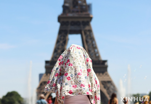 16일(현지시간) 프랑스 파리의 에펠탑 근처에서 한 사람이 블라우스를 머리에 쓰고 뜨거운 햇볕을 가리고 있다. 프랑스 기상 당국은 이번 주말 전국 대부분 지역에 폭염 경보를 내리고 주민들에게 주의를 요청했다. (출처: 뉴시스)