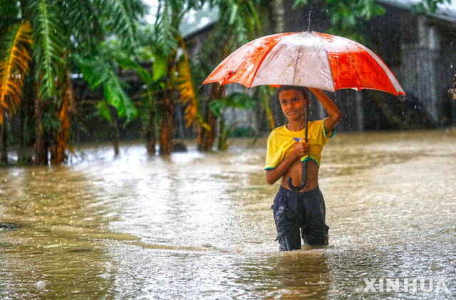 18일(현지시간) 방글라데시 실레트 도로가 침수된 가운데 한 소년이 이 길을 걷고 있다. 지난 16일부터 폭우와 홍수, 이로 인한 산사태 등이 방글라데시와 인도를 강타하면서 최소 59명이 숨지고 수백만명의 발이 묶였다. (출처: 뉴시스)