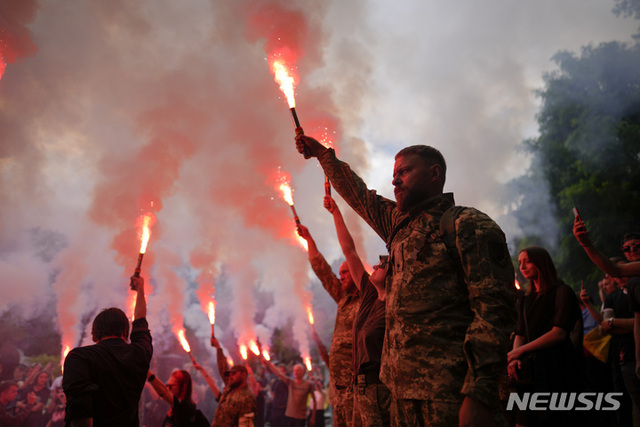 18일(현지시간) 우크라이나 수도 키이우에서 열린 군인 로만 라투슈니의 장례식에서 동료 군인들이 조명탄을 들고 있다. 라투슈니는 이지움 근처에서 벌어진 전투 중 사망했다. (출처: 뉴시스)