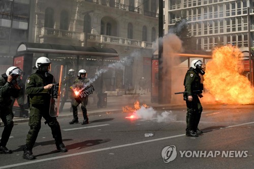 5일(현지시간) 아테네에서 열린 시위에서 시위대와 충돌하는 동안 휘발유 폭탄이 폭발하자 전경들이 반응하고 있다. (출처: AFP, 연합뉴스)