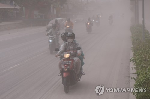 (출처: 로이터, 연합뉴스) 11일(현지시간) 인도네시아 중부 자바 족자카르타 인근 므라피 화산이 폭발하면서 화산재가 날리는 도로를 오토바이가 달리고 있다.