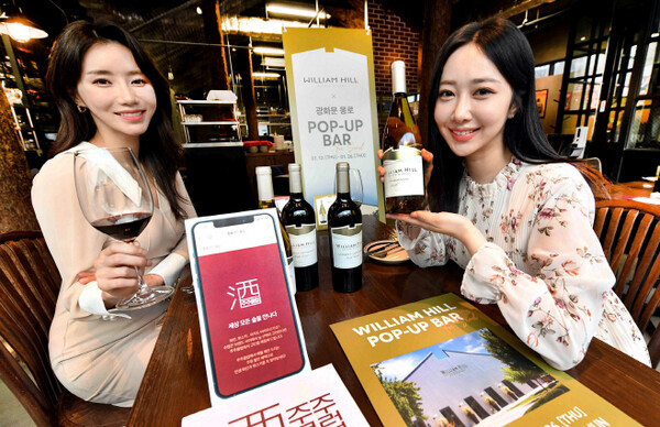 모델들이 서울시 중구 광화문 몽로에 운영 중인 ‘홈플러스×윌리엄힐 팝업바’에서 홈플러스가 단독 론칭한 ‘윌리엄 힐 노스 코스트’ 와인을 소개하고 있다. (제공: 홈플러스)