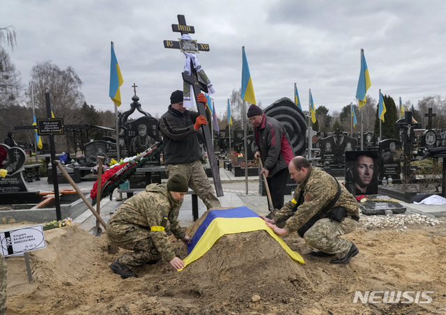 서방 정보당국은 러시아-우크라이나 전쟁 1년을 맞아 최대 30만명의 러시아·우크라군이 죽거나 다친 것으로 분석했다. 영국국방부는 러시아 사상자 수를 17만 5000∼20만명에 이르고 전사자 수는 4만∼6만명으로 추산했다. 우크라군은 자국군 사상자 수를 발표하지 않고 있지만 서방 당국은 우크라군의 사상자가 약 10만명이 발생한 것으로 보고 있다. 사진은 우크라이나 군인들이 키이우의 한 공동묘지에서 러시아군에 의해 숨진 동료의 무덤에 국기를 덮어주고 있다. (출처: 뉴시스)