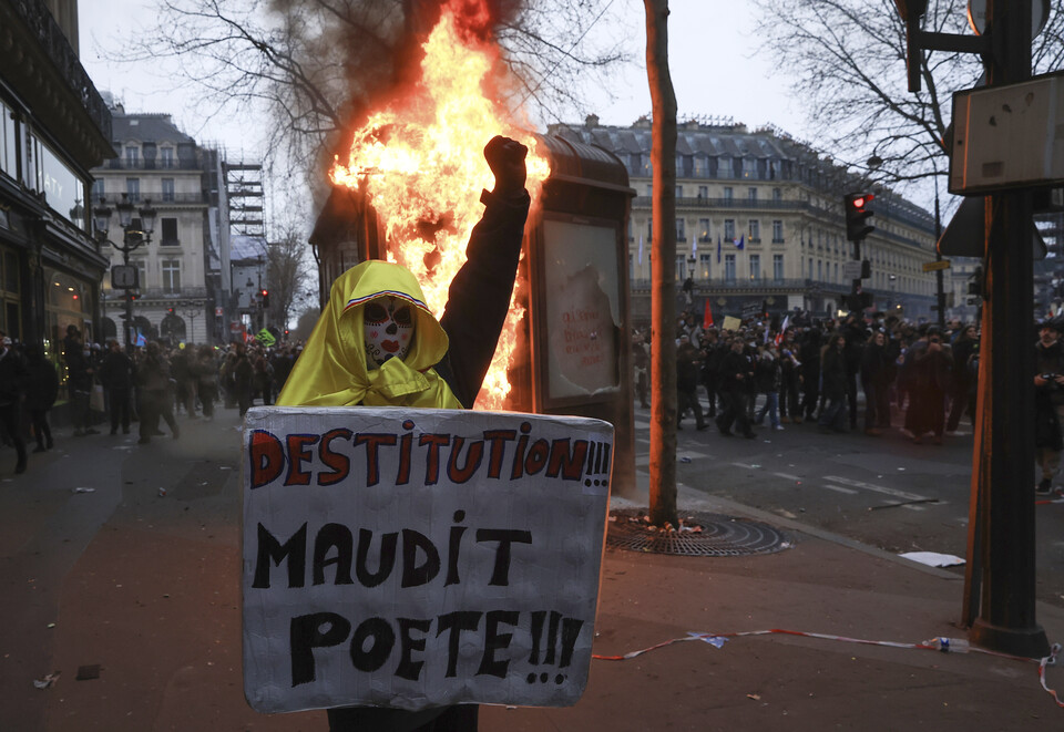 23일(현지시간) 프랑스 파리에서 정부의 연금개혁을 반대하는 9번째 전국 규모 시위가 벌어져 경찰과 시위대가 유혈 충돌하는 가운데 한 시위자가 "저주받은 시인의 궁핍"이라고 적힌 플래카드를 들고 있다. (출처: AP/연합뉴스)