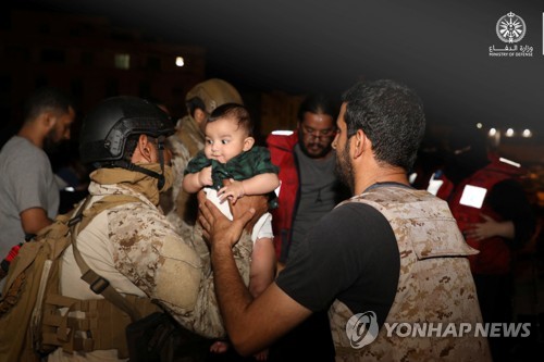 22일(현지시간) 사우디 왕실 해군이  사우디 해군 함정을 통해 수단 항구도시 포트 수단에서 사우디 제다항으로 대피해온 한 가족의 아이를 넘겨받고 있다. (로이터/연합뉴스)