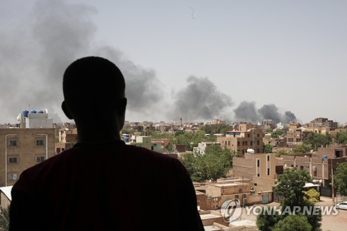 한 주민이 수단 수도 하르툼에서 군벌 간 전투로 치솟는 연기를 바라보고 있다. (AP/연합뉴스)