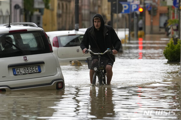 17일(현지시각) 이탈리아 에밀리아-로마냐주 카스텔 볼로네제 마을에서 자전거를 탄 사람이 침수 거리를 힘겹게 헤쳐 나가고 있다. 가뭄이 이어지던 이탈리아 북부에 폭우가 내리면서 홍수가 발생, 최소 8명이 숨지고 주민 수천 명이 대피했다. (AP/뉴시스)