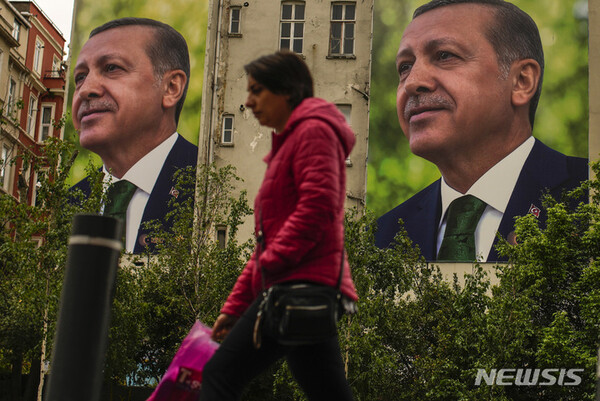 튀르키예 이스탄불에서 15일 레제프 타이이프 에르도안 대통령의 광고판 앞을 한 여성이 지나가고 있다. 에르도안 대통령의 30년에 걸친 권위주의 통치를 또다시 연장할 것인지 아니면 보다 개혁 성향의 민주체제로 전환할 것인지를 가리는 튀르키예 대선의 최종 결과는 결국 28일 결선투표를 통해 가려지게 됐다. (AP/뉴시스)