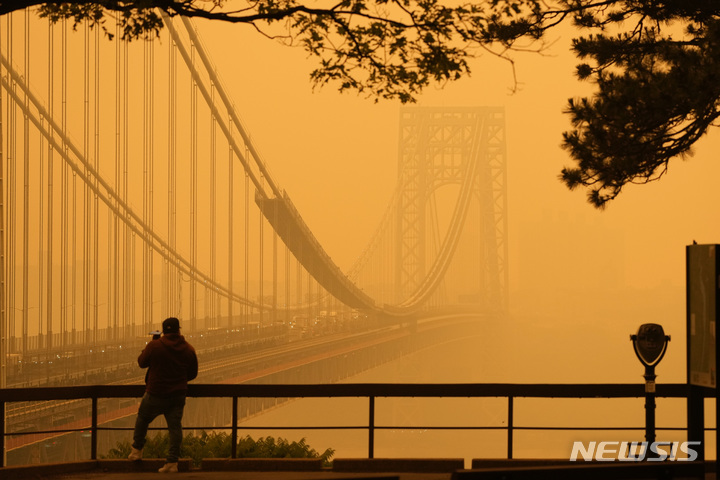 7일(현지시각) 미 뉴저지주 포트리에서 한 남성이 캐나다 산불로 오염된 대기 속 조지 워싱턴 다리를 바라보며 전화 통화를 하고 있다. (AP/뉴시스)