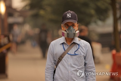 캐나다에서 발생한 산불 연기가 미국의 동부 지역까지 확산하는 가운데 7일(현지시간) 한 남성이 방진 마스크를 쓴 채 뉴욕 거리를 걷고 있다. 이날 미국 환경보호청(EPA)은 1억명 이상의 주민에게 대기질 경보를 발령했다. (로이터=연합뉴스)
