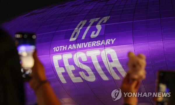 (그룹 방탄소년단(BTS) 데뷔 10주년을 하루 앞둔 12일 오후 외국인 관광객이 BTS를 상징하는 보랏빛으로 물든 서울 동대문디자인플라자(DDP) 건물을 촬영하고 있다. (출처: 연합뉴스)