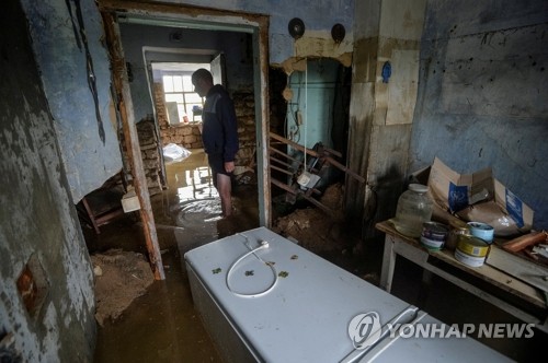 우크라이나 헤르손주 인근 아파나시이우카의 주민이 12일(현지시간) 물에 잠긴 자신의 집을 둘러보고 있다. (로이터/연합뉴스)