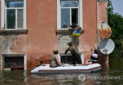 우크라이나 군인들이 8일(현지시간) 카호우카 댐 파괴로 침수 피해를 입은 남부 헤르손주 주민에게 식량을 전달하고 있다. (AFP/연합뉴스)