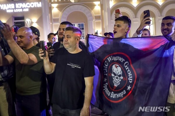 24일(현지시각) 러시아 로스토프나도누 주민들이 바그너 용병 그룹 깃발을 들고 이곳을 떠날 준비를 하고 있는 바그너 그룹 병사들을 향해 환호하고 있다. (AP/뉴시스)