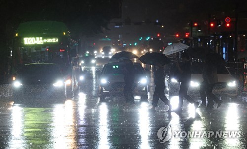 (서울=연합뉴스) 서울 전역에 호우주의보가 발효 중인 4일 오후 서울 광화문 광장에서 시민들이 우산을 쓴 채 걸어가고 있다.