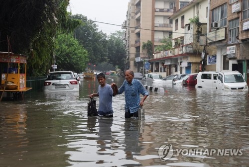 8일(현지시간) 인도 뉴델리 시민들이 폭우로 물에 잠긴 거리를 건너가고 있다. 현지 매체 NDTV는 이번 폭우로 지금까지 최소 12명이 사망했다고 9일 보도했다. (로이터/연합뉴스)