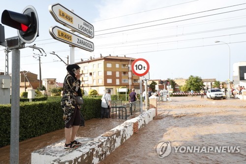 7일(현지시간) 스페인 북부 라리오하주 린콘델소토 마을에 폭우가 내린 뒤 주민들이 침수된 도로를 바라보고 있다. (EPA/연합뉴스)