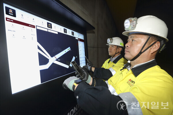 KT 광산안전DX 스마트기기를 장착한 광산 작업자들이 상동광산 입구의 갱도 출입 관제 모니터를 바라보며 광산 내부 상황을 확인하고 있다. (제공: KT) ⓒ천지일보 2023.07.11.