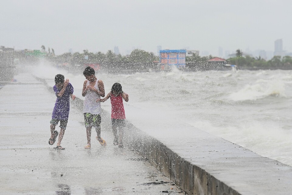태풍 독수리가 필리핀 루손섬 북단에 가까워진 26일(현지시간) 아이들이 필리핀 수도권 메트로 마닐라 나보타스시의 한 해변을 걷고 있다. AP 통신은 이날 태풍으로 침수와 정전 피해가 발생하고 1만명 이상 대피했다고 전했다. (AFP/연합뉴스)