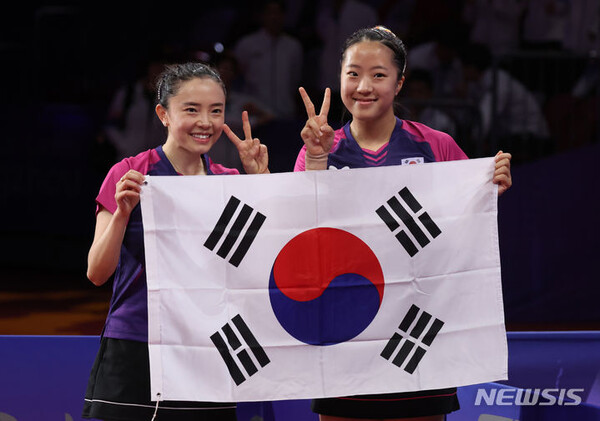[항저우=뉴시스] 2일 중국 항저우 공슈 캐널 스포츠파크 짐내시움에서 열린 2022 항저우 아시안게임 여자 탁구 복식 결승 한국 대 북한 경기, 세트스코어 4:1로 북한에 승리를 거두고 금메달을 획득한 전지희, 신유빈이 태극기를 들고 인사를 하고 있다. 2023.10.02.