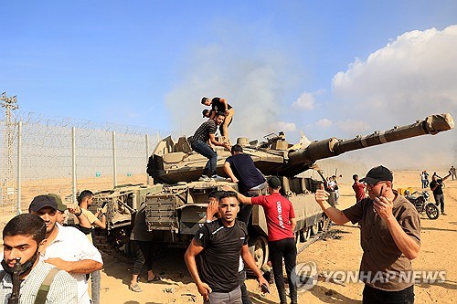 팔레스타인 무장세력이 7일(현지시간) 남부 가자지구의 칸 유니스에서 이스라엘 국경 철책을 넘은 후 이스라엘 탱크를 장악하고 있다. (출처: UPI, 연합뉴스)