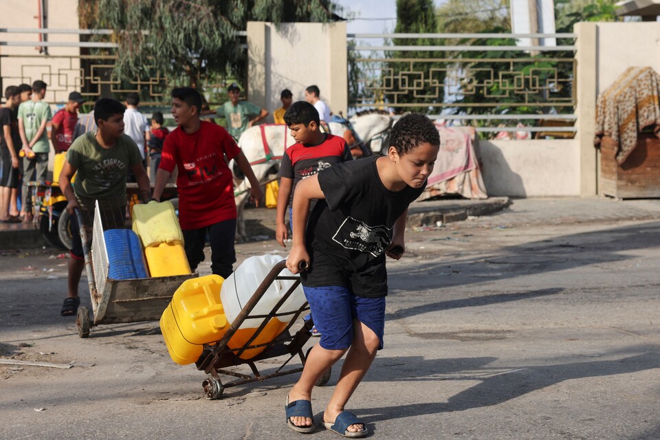 22일(현지시간) 라파에서 학생들이 이집트 국경 검문소를 통해 보급된 식수를 옮기고 있다. (AFP/연합뉴스) 2023.10.23.