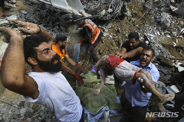 지난 24일(현지시간) 가자시티에 대한 이스라엘의 공습 이후 주민들이 파괴된 집 잔해 아래에서 발견된 아이의 시신을 옮기고 있다. (출처: 뉴시스)