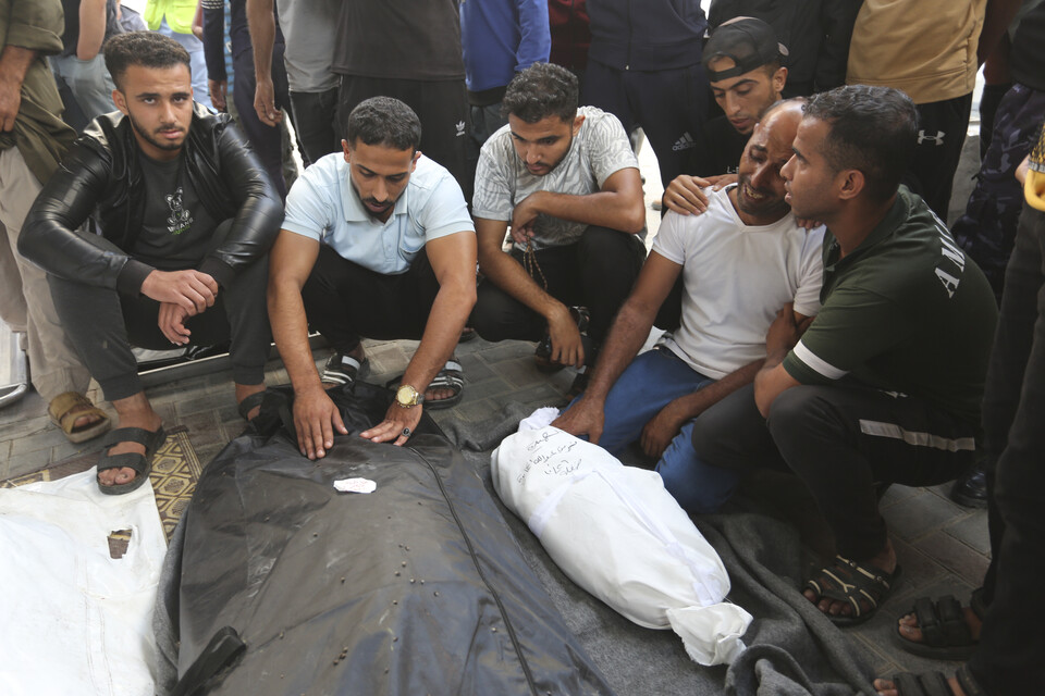 27일(현지시각) 가자지구 라파의 한 시신공시소 밖에서 팔레스타인 주민들이 이스라엘의 가자지구 폭격으로 숨진 일가의 시신 주변에 앉아 흐느끼고 있다. (AP/뉴시스) 2023.10.30.
