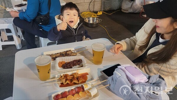 원주 우산천변에서 개최된 주민자치 가을축제에 엄마와 함께 방문한 한 어린이가 테이블에 있는 음식을 맛있게 먹으며 따봉 엄지척을 하며 즐거워하고 있다. ⓒ천지일보 2023.11.02.