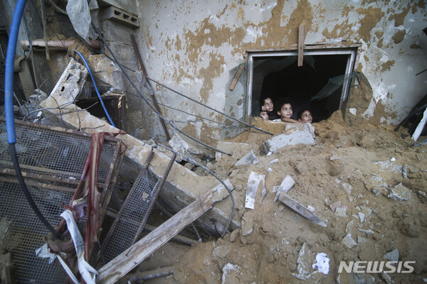 15일(현지시각) 이스라엘의 공습으로 파괴된 가자지구 라파 마을의 파괴된 건물 창에서 팔레스타인 어린이들이 천진한 표정으로 밖을 내다보고 있다. (출처: AP/뉴시스)