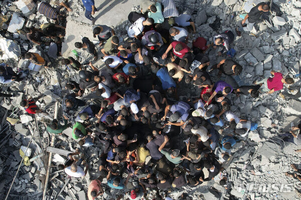 [가자지구=AP/뉴시스] 5일(현지시각) 가자지구 알마가지 난민촌 주민들이 이스라엘의 공습으로 파괴된 건물 구덩이에 모여 생존자를 찾고 있다. 2023.11.06.