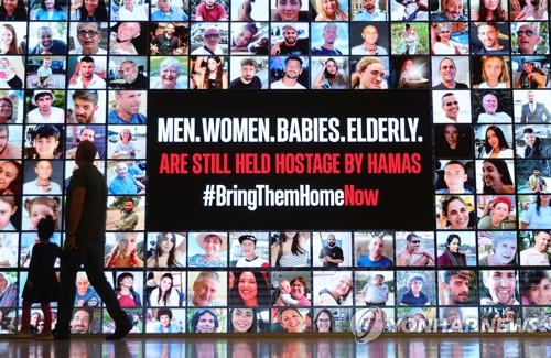 (출처: EPA, 연합뉴스) 이스라엘이 22일(현지시간) 하마스에 잡힌 인질 50명을 석방하는 조건으로 ‘4일간 임시휴전’을 승인했다. 사진은 이스라엘 텔아비브 박물관 방문객들이 하마스에 납치된 인질들의 사진을 보여주는 광고판을 지나가고 있는 모습