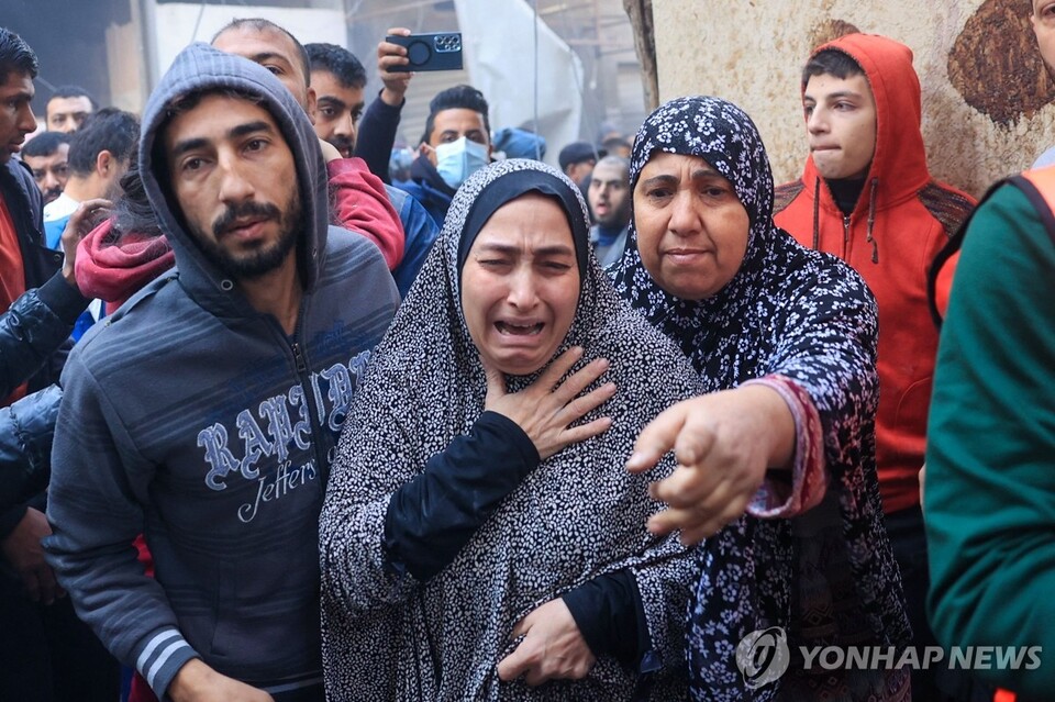 1일(현지시간) 가자지구 남부 라파 난민촌에서 이스라엘의 공습으로 다친 부상자들이 구급차로 이송되는 가운데 한 팔레스타인 여성이 울부짖고 있다. 이스라엘군은 이날 팔레스타인 무장 정파 하마스가 휴전 협정을 위반하고 자국을 공격했다며 가자지구에서 전투를 재개했다. (AFP/연합뉴스) 2023.12.02.
