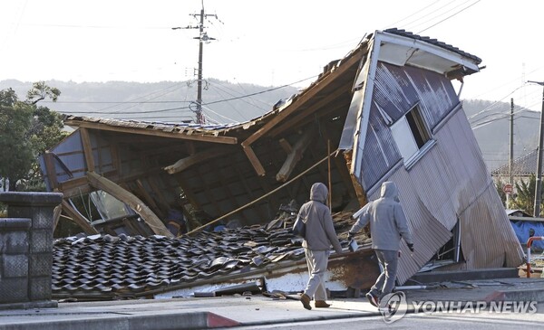 2일 일본 이시카와현 시카마치에서 사람들이 지진으로 무너진 건물을 지나가고 있다. 새해 첫날인 전날 이시카와현에서 규모 7.6의 강진이 발생한 뒤 주변 지역에서 여러 차례 여진이 관측됐다. (출처: 연합뉴스)