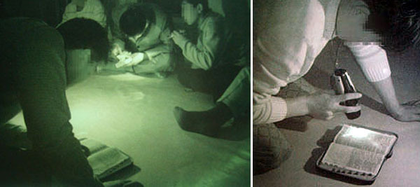 북한의 지하교회에 모인 신자들이 희미한 손전등 아래서 성경을 몰래 읽고 있다. (제공 : 순교자의 소리)