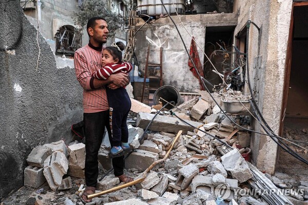 (라파 AFP=연합뉴스) 한 팔레스타인 남성이 8일(현지시간) 팔레스타인 가자지구 남부 라파에서 이스라엘군 공습으로 파괴된 한 아파트 잔해 가운데 어린 딸을 안고 서 있다. (출처: 연합뉴스)
